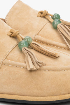 Detailaufnahme der dekorativen Quaste mit grüner Perle auf dem beigen Velours-Loafer