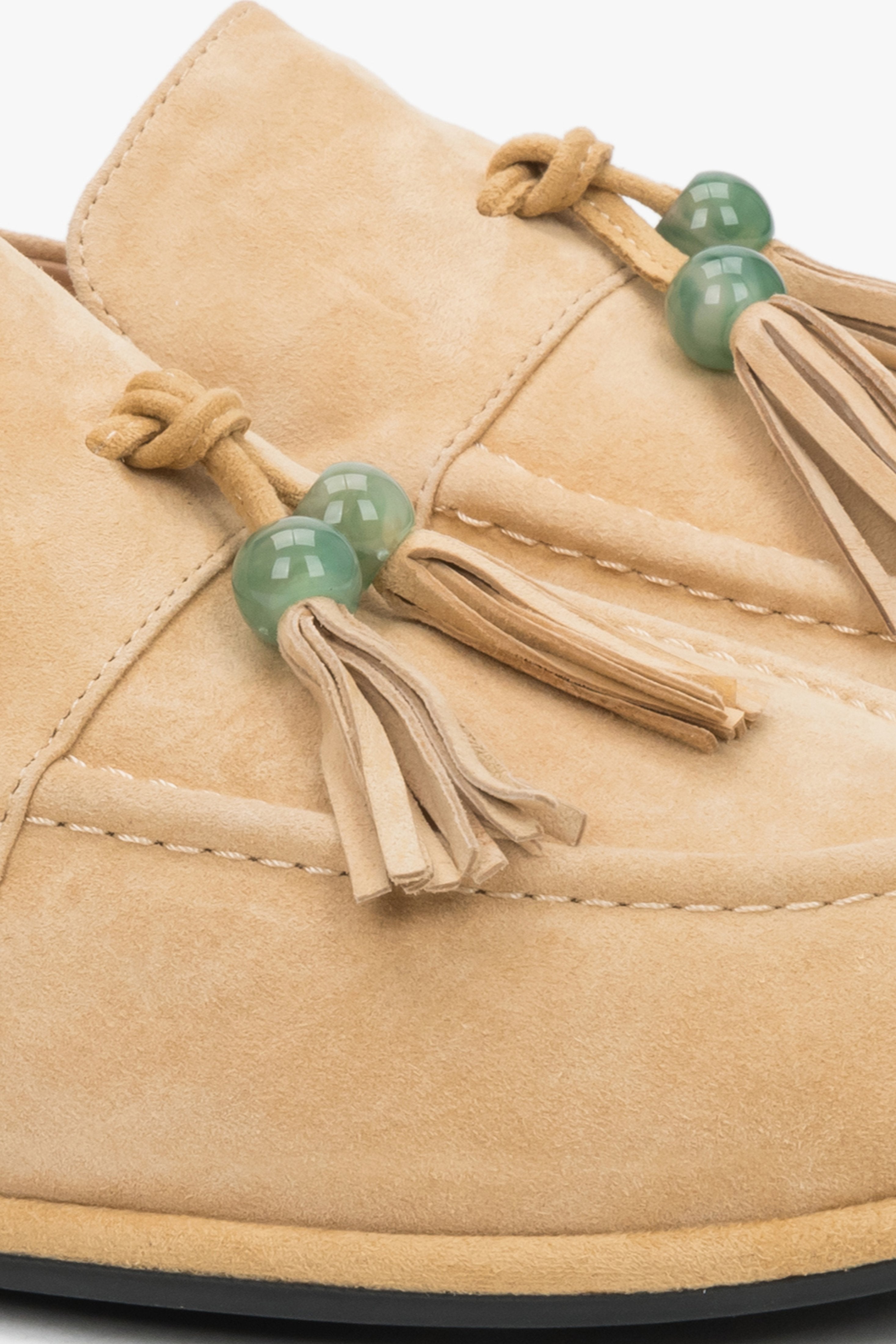 Detailaufnahme der dekorativen Quaste mit grüner Perle auf dem beigen Velours-Loafer