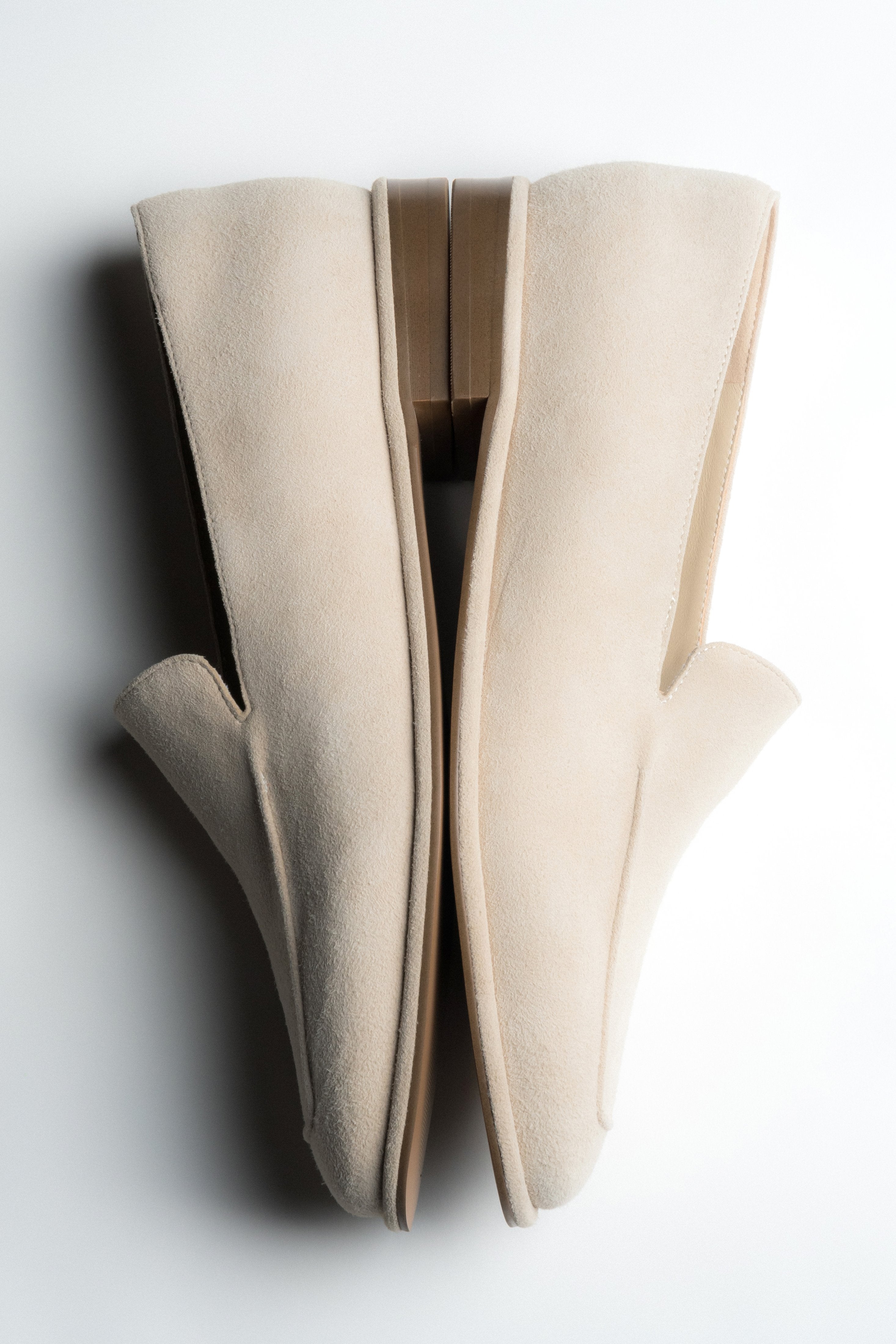 Beige Damen-Loafer aus Veloursleder in künstlerischer Ansicht mit langer Silhouette