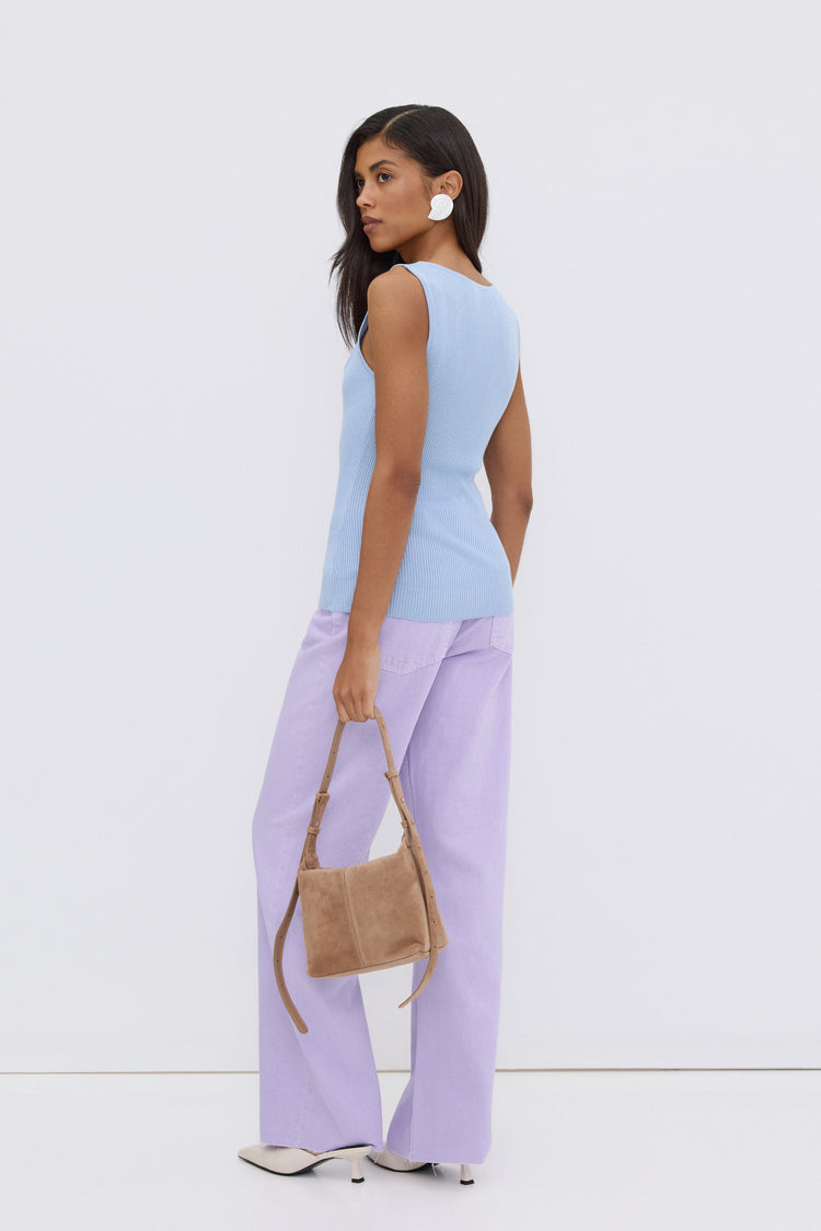 Model steht in einem sommerlichen Outfit und präsentiert die beigefarbene Leder-Schultertasche