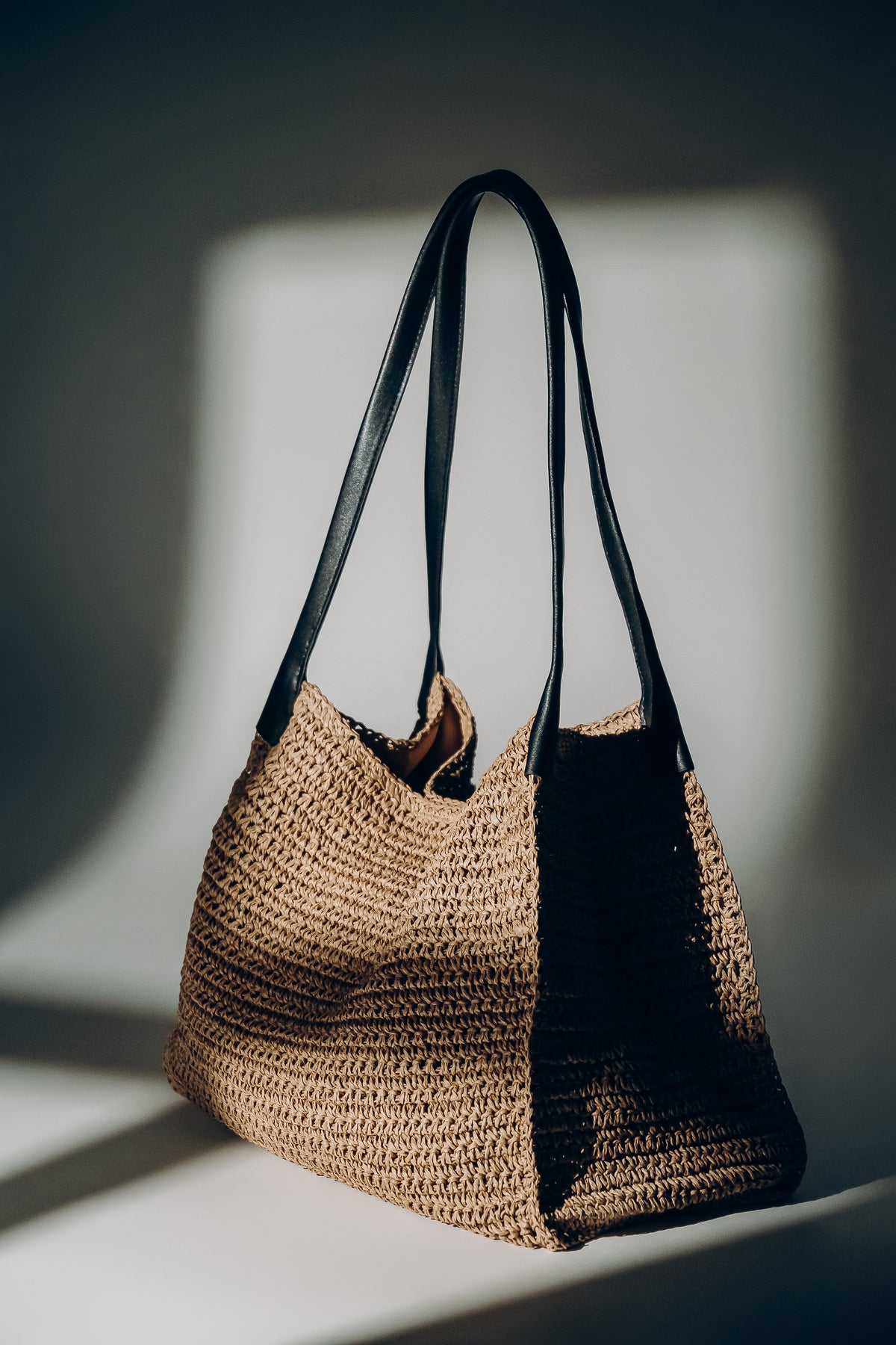 Beige Damen-Shopper-Tasche aus Stroh in Lifestyle-Aufnahme auf dunklem Hintergrund