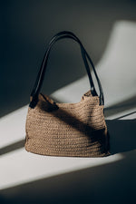 Beige Damen-Shopper-Tasche aus Stroh in künstlerischer Ansicht mit schwarzen Henkeln