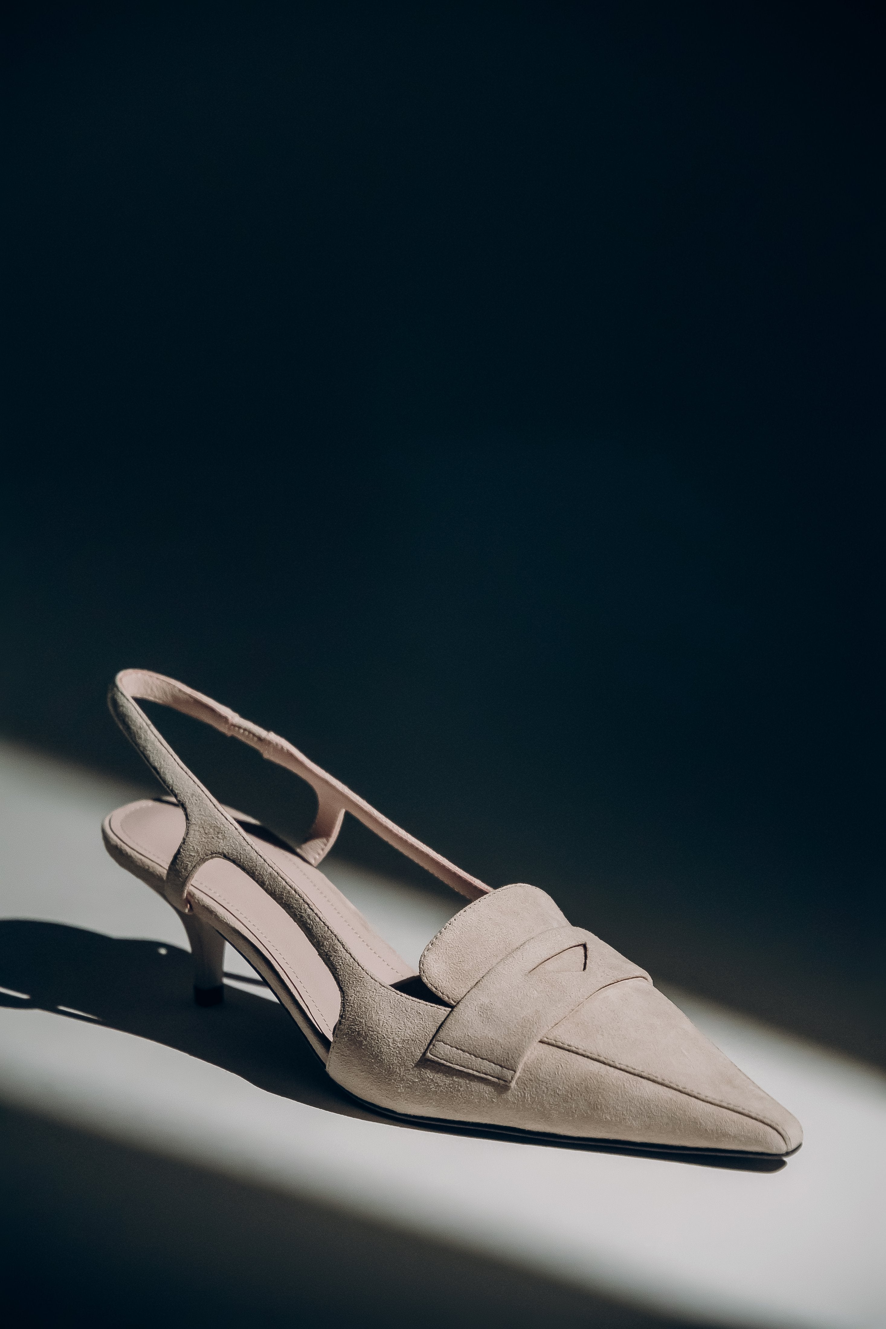 Beige Damen-Slingpumps aus echtem Velours in künstlerischer Ansicht auf dunklem Hintergrund