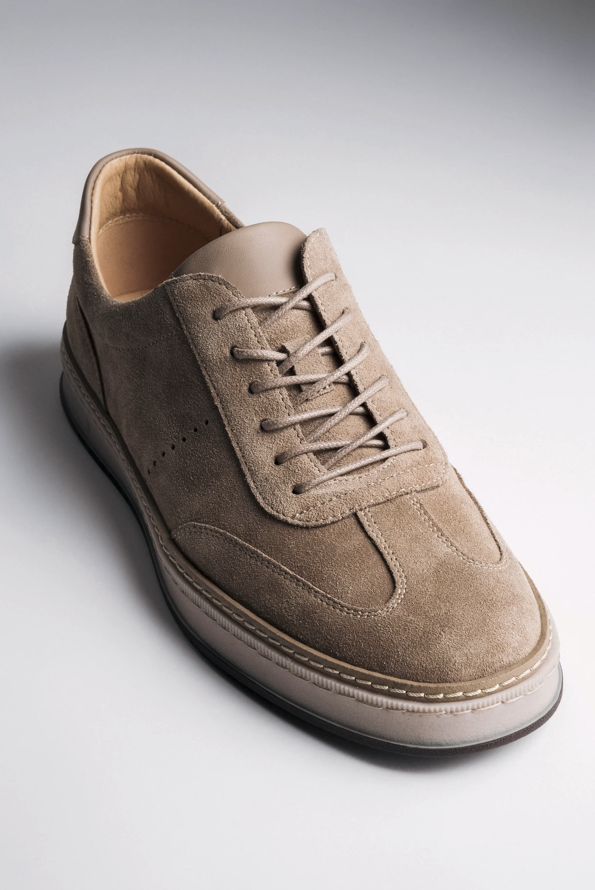 Schräge Nahaufnahme des beigen Herren-Sneakers aus weichem Veloursleder.