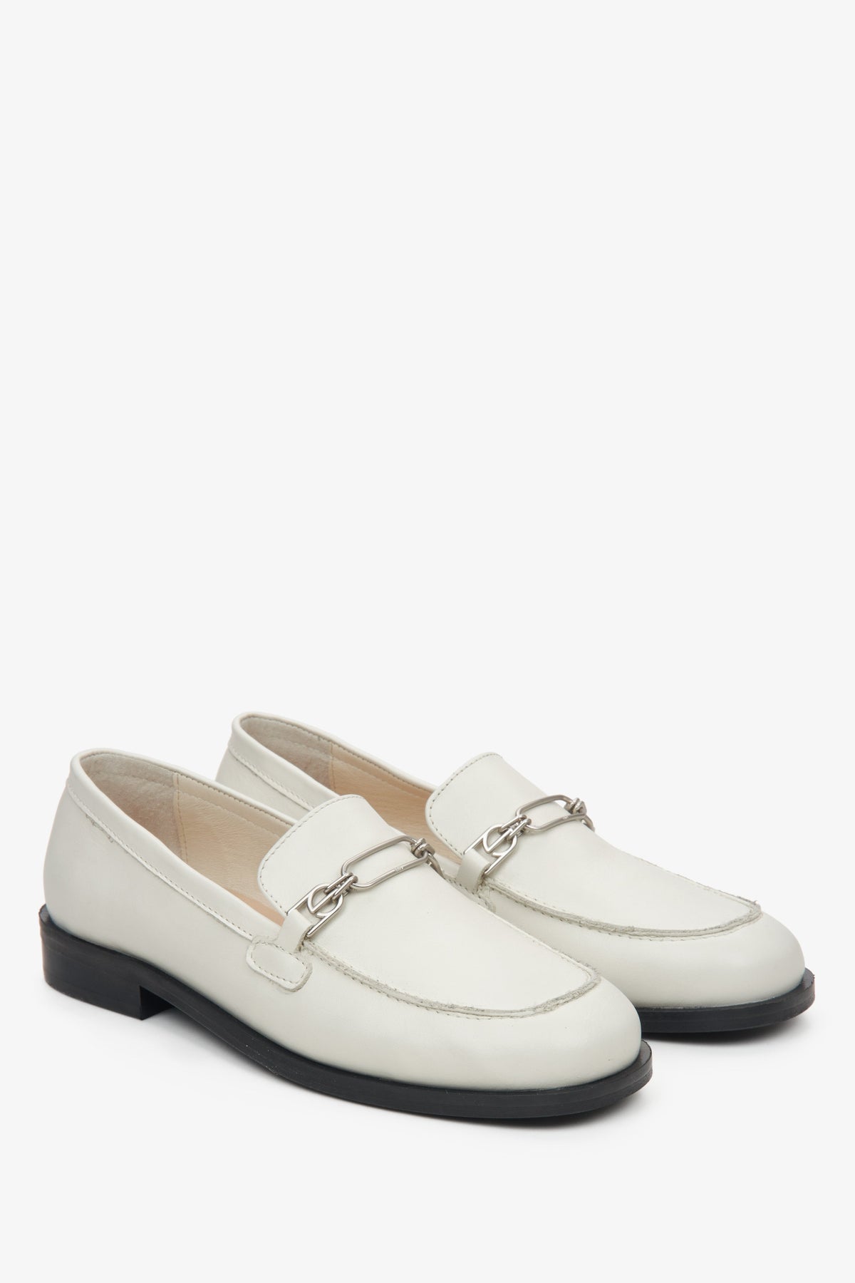 Schräge Frontalansicht des Paares heller Leder-Loafer mit feinem Schmuckdetail