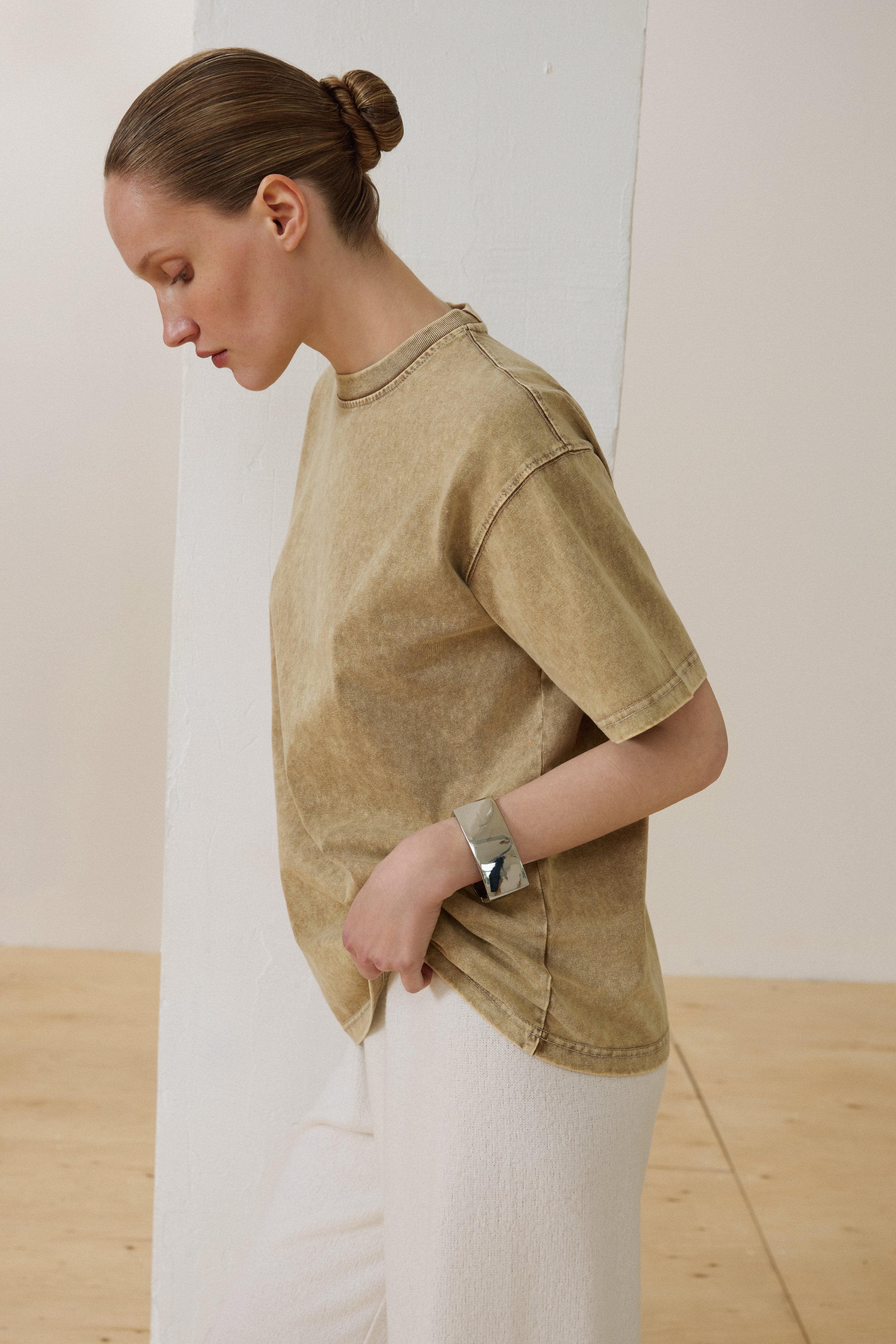 Model trägt beiges Damen-T-Shirt aus Baumwolle mit Washed-Effekt leicht gebeugt