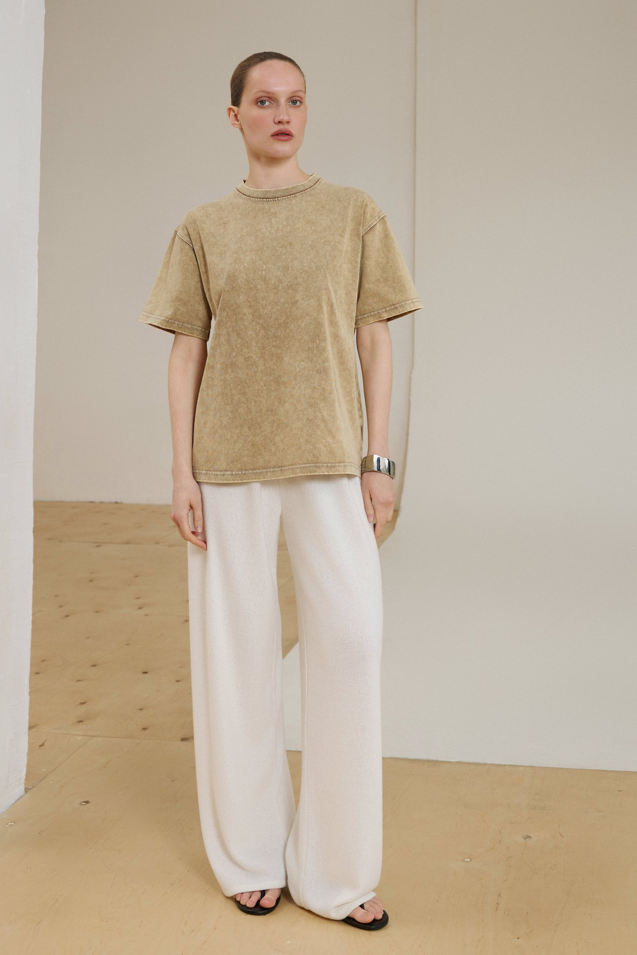 Model in voller Länge mit beigem Boxy-T-Shirt und weißer Hose