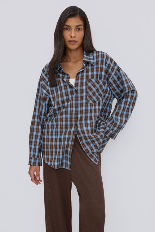 Nahaufnahme des Models in der lässig geöffneten blau-braun karierten Oversize-Hemdbluse