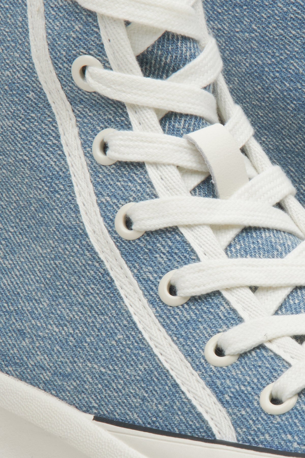 Detailaufnahme der weißen Schnürung und der textilen Struktur des blauen Sneakers