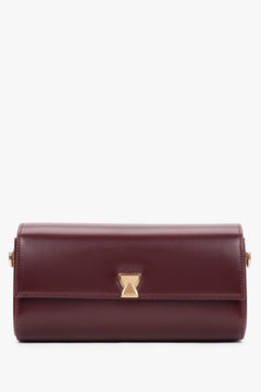 Frontale Ansicht der länglichen bordeauxroten Baguette-Clutch mit geometrischem Goldverschluss