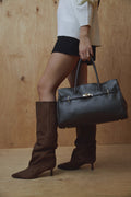 Model präsentiert die braunen Veloursstiefel zu einem herbstlichen Outfit mit großer schwarzer Tasche 
