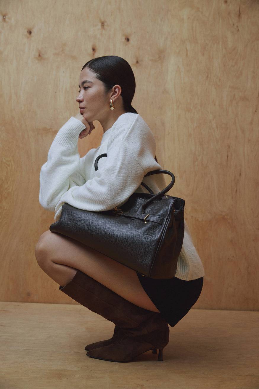 Model hockt und zeigt die flexiblen braunen Veloursstiefel in einem eleganten, urbanen Look