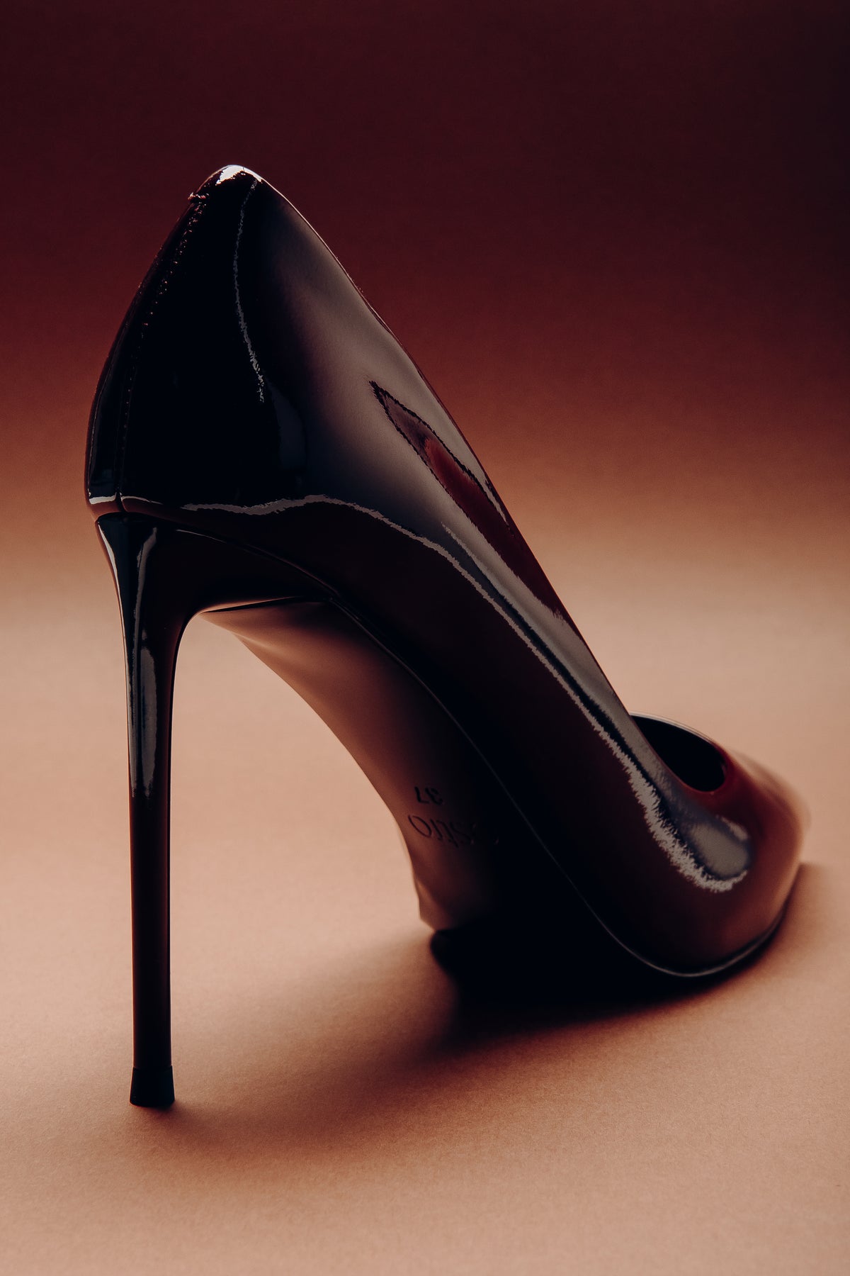 Detaillierte Rückansicht des schmalen Pfennigabsatzes und der eleganten Fersenform eines schwarzen Lackleder-Pumps