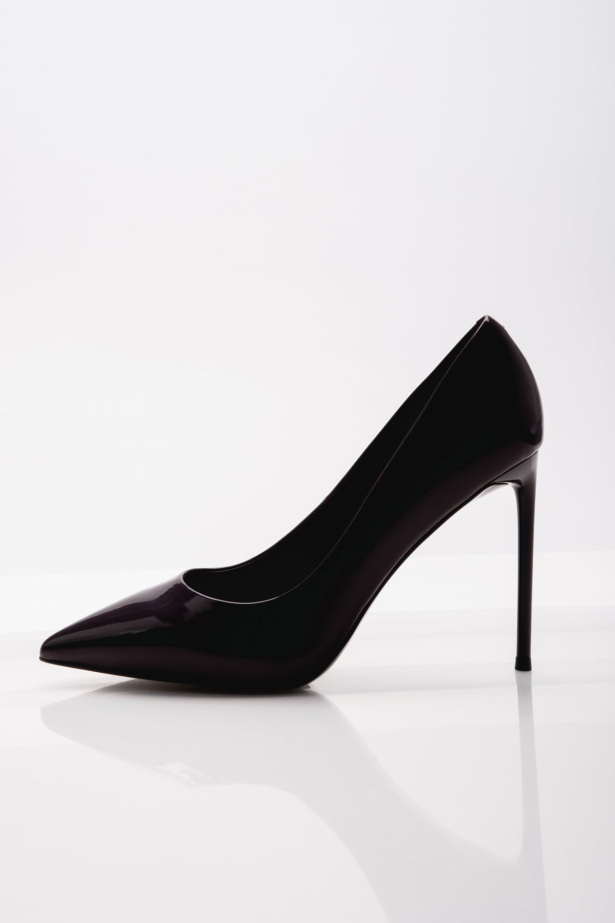 Klassische Seitenansicht des schwarzen Damen-Stilettos aus Lackleder auf weißem, reflektierendem Untergrund