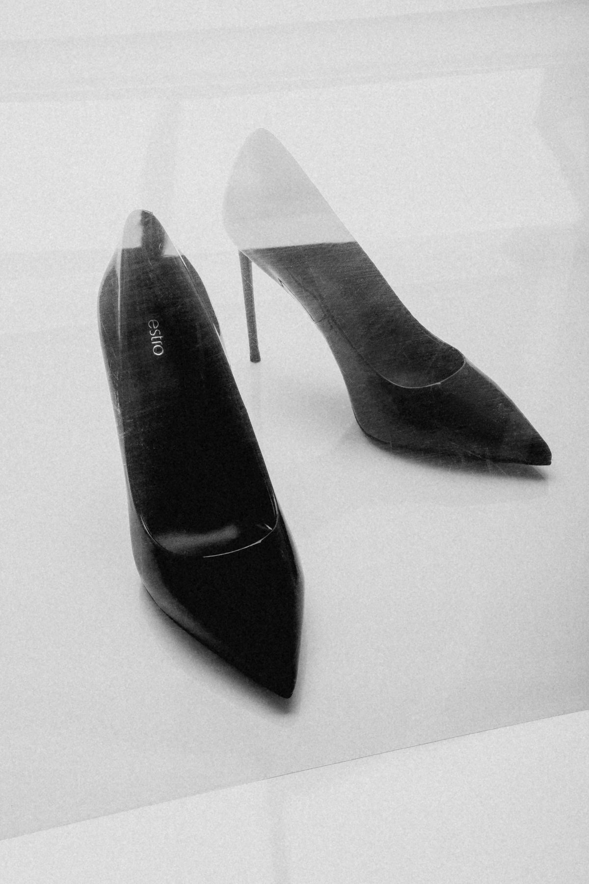 Stimmungsvolle, künstlerische Aufnahme des burgundroten Schuhpaars auf hellem, reflektierendem Untergrund