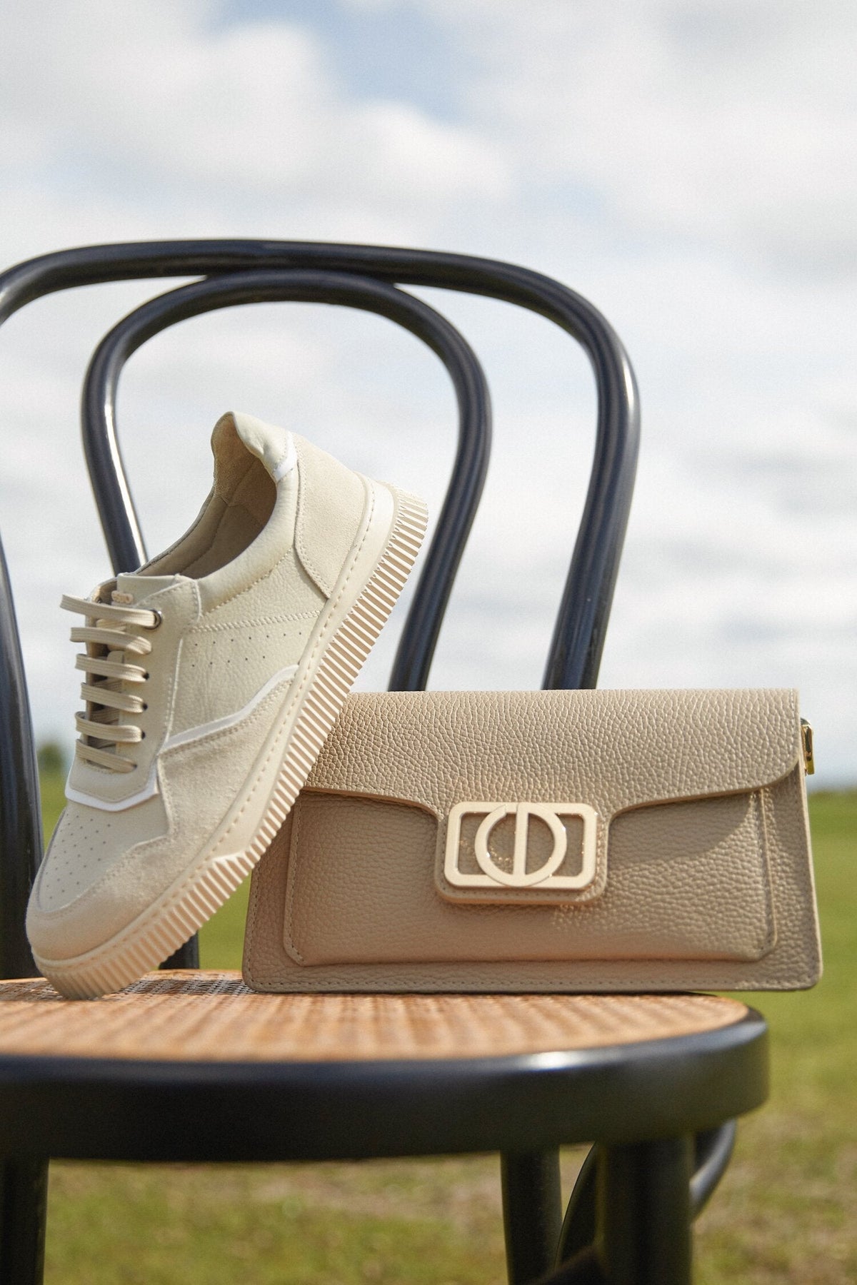 Die creme-beigen Velours-Sneaker dekoriert neben einer Handtasche auf einem Stuhl