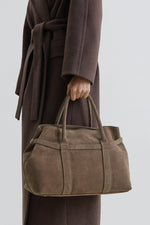 Model trägt die dunkelbeige Velours-Tote-Bag am kurzen Griff in der Hand
