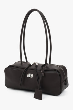 Schräge Frontalansicht der dunkelbraunen Ledertasche mit dekorativen Lederbändchen am Reißverschluss
