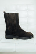 Dunkelbrauner Damen-Chelsea-Boot aus Veloursleder, seitlich präsentiert auf einem weißen Polstersessel