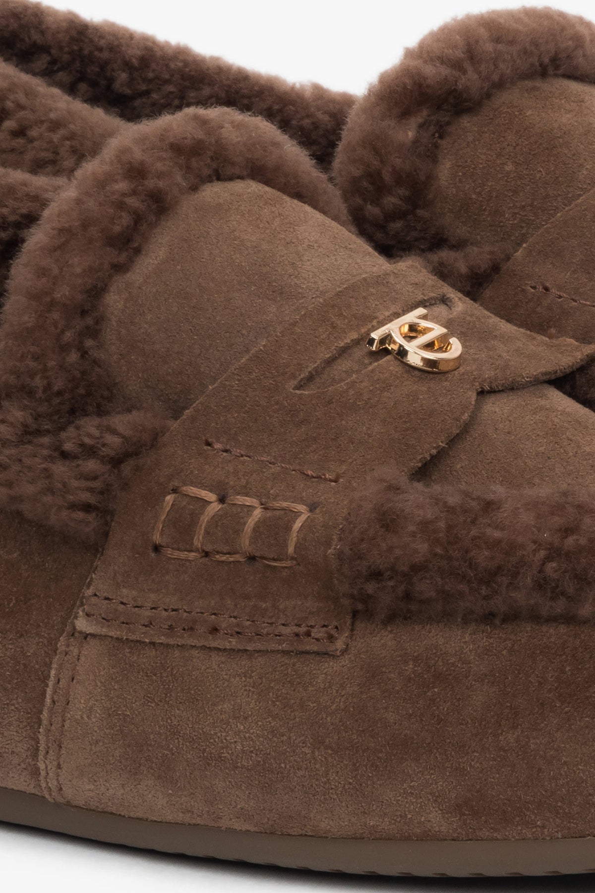 Detailansicht des goldenen Estro-Logos und der Pelzränder auf dem braunen Veloursleder