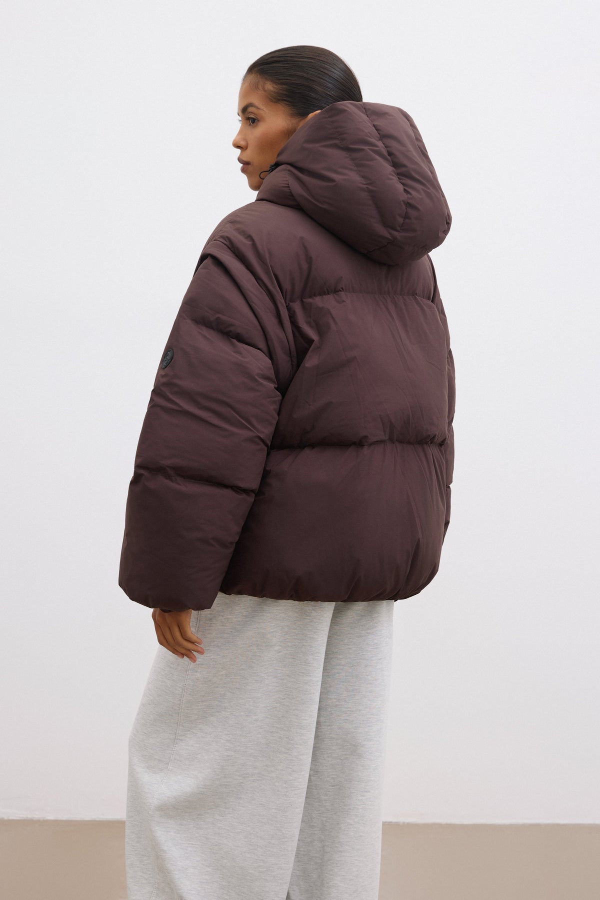 Rückansicht der dunkelbraunen Steppjacke, präsentiert an einem Model im urbanen Look 