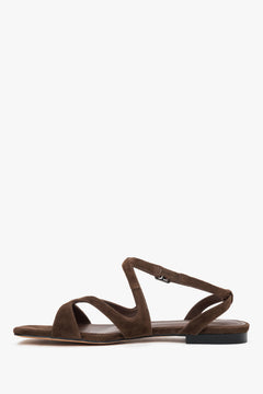 Linkes Seitenprofil der braunen Sandalen mit gekreuzten Riemen iund flachem Absatz.