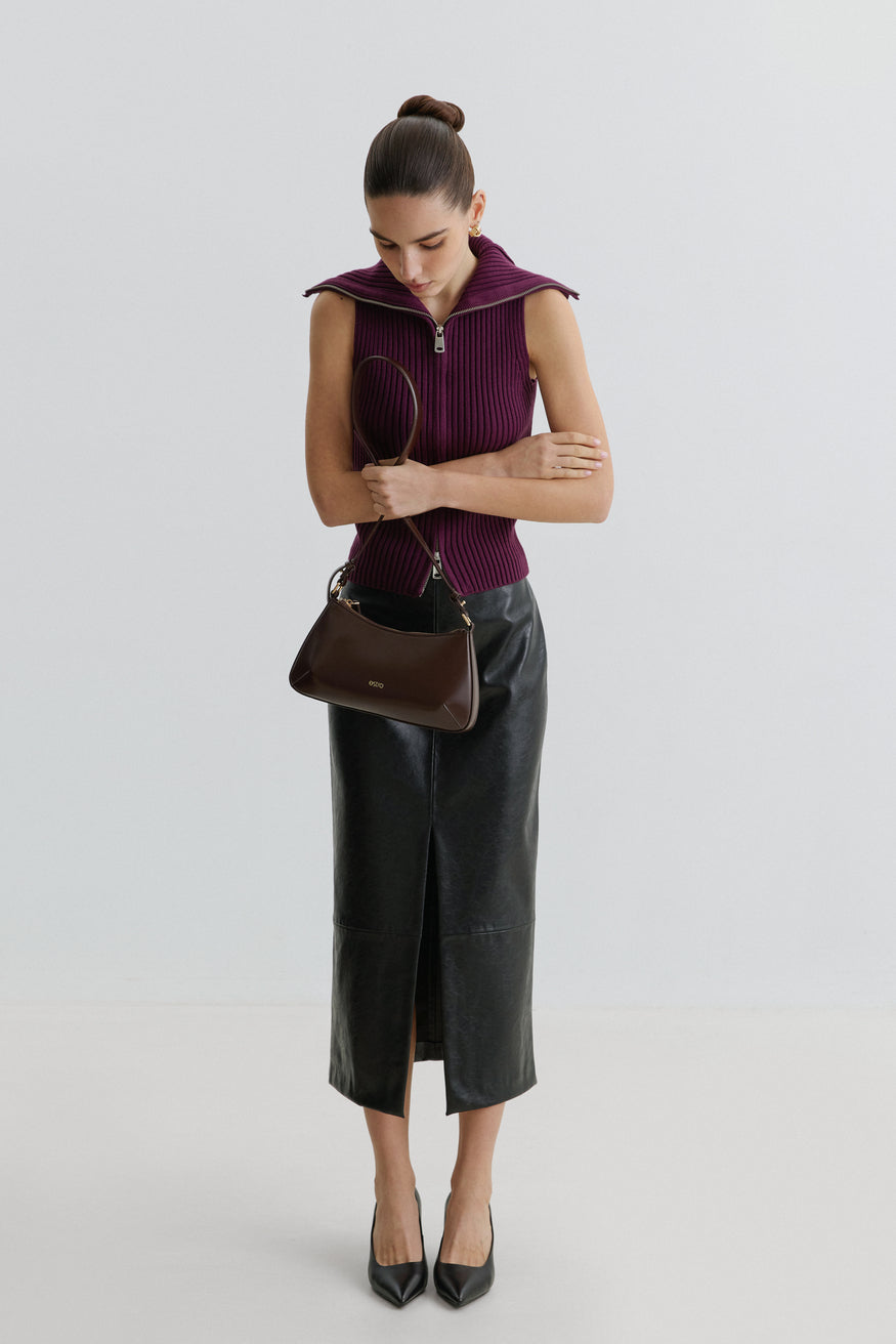 Lifestyle-Aufnahme eines Models im bordeauxroten Top und schwarzen Midirock, das die dunkelbraune Estro-Ledertasche über der Schulter trägt
