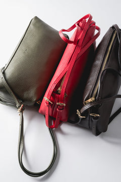 Kreative Präsentation mehrerer länglicher Ledertaschen in verschiedenen Farben nebeneinander 