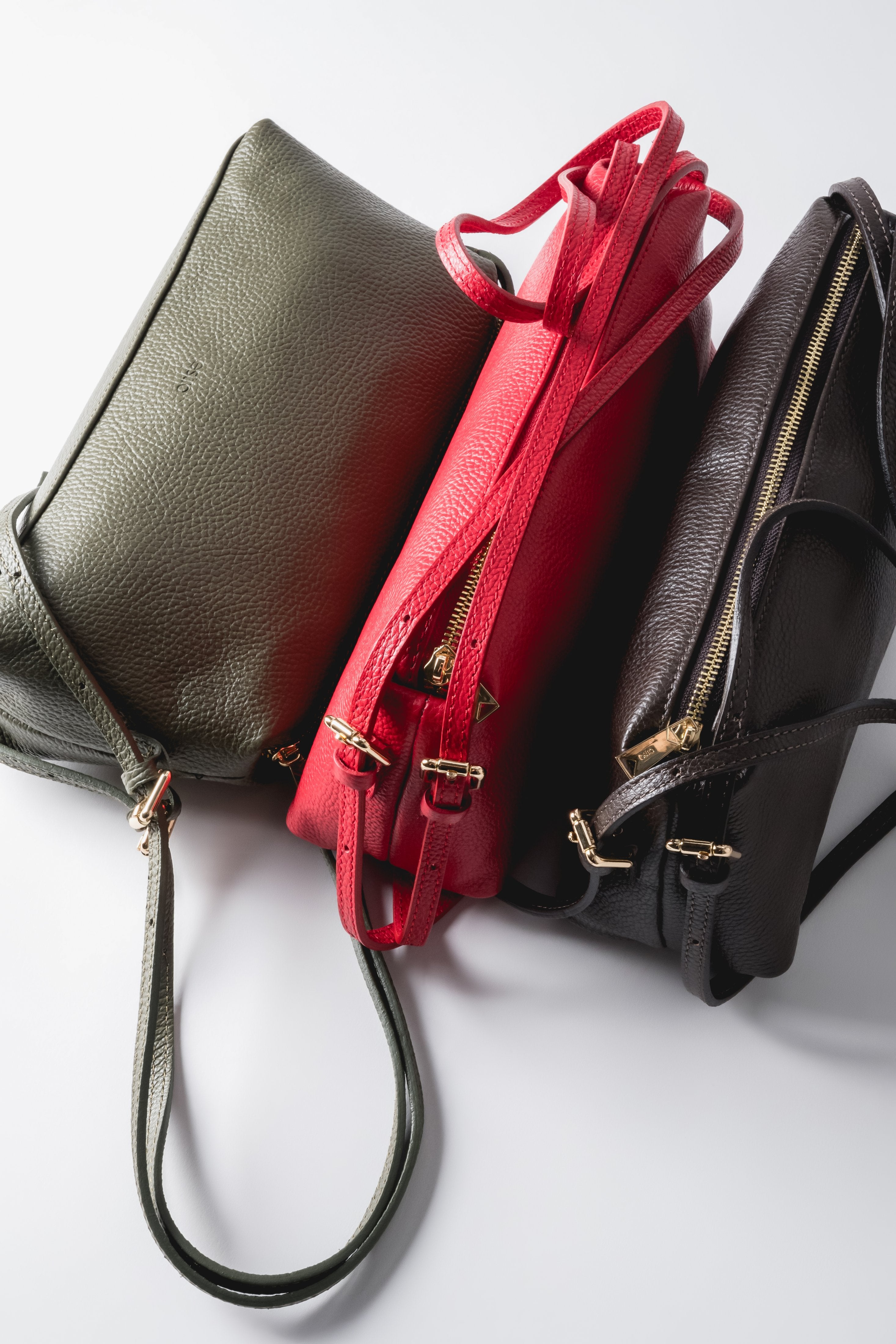 Kreative Präsentation mehrerer länglicher Ledertaschen in verschiedenen Farben nebeneinander 