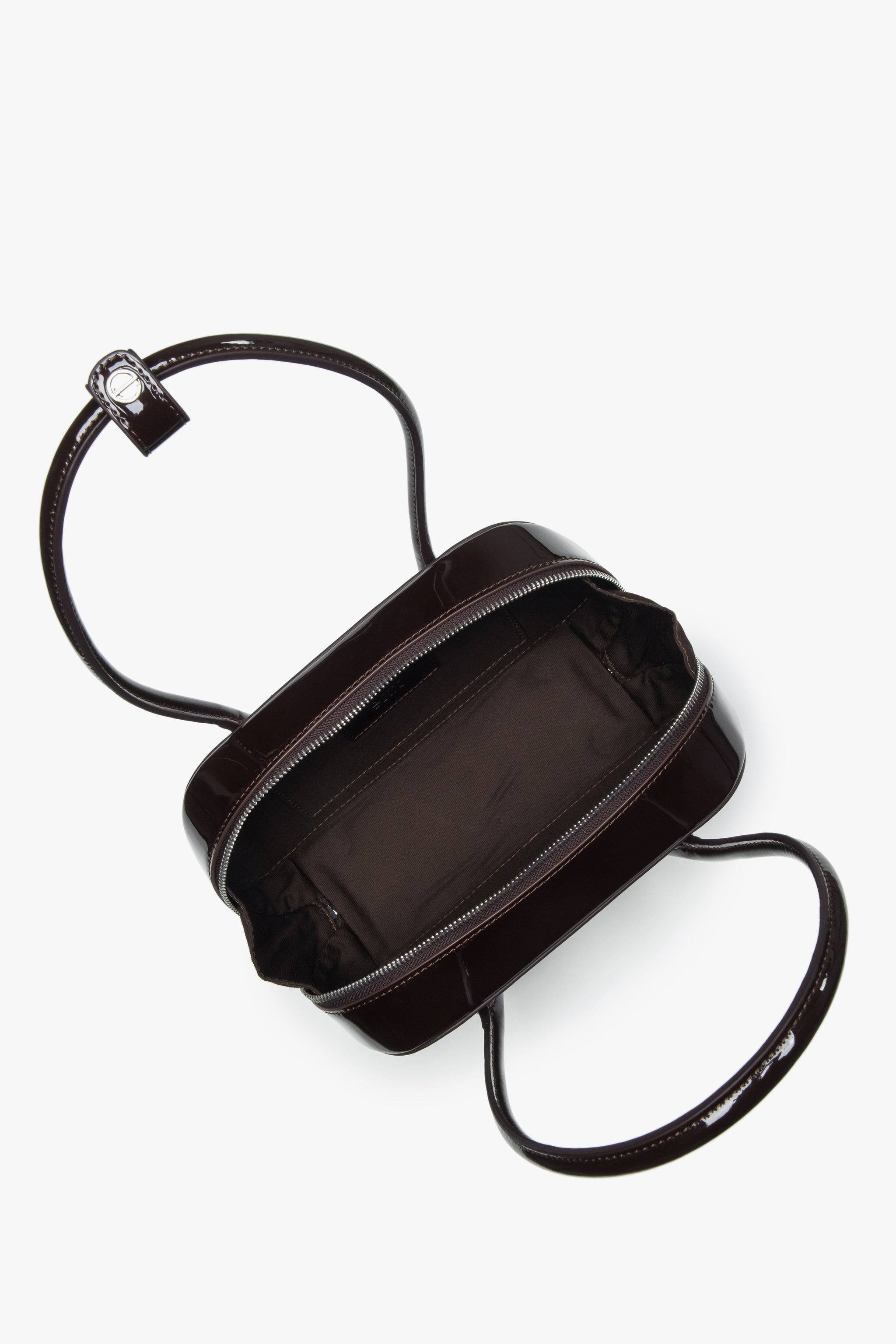 Draufsicht auf die geöffnete Lackledertasche mit Reißverschluss und Logo-Pin am Griff.