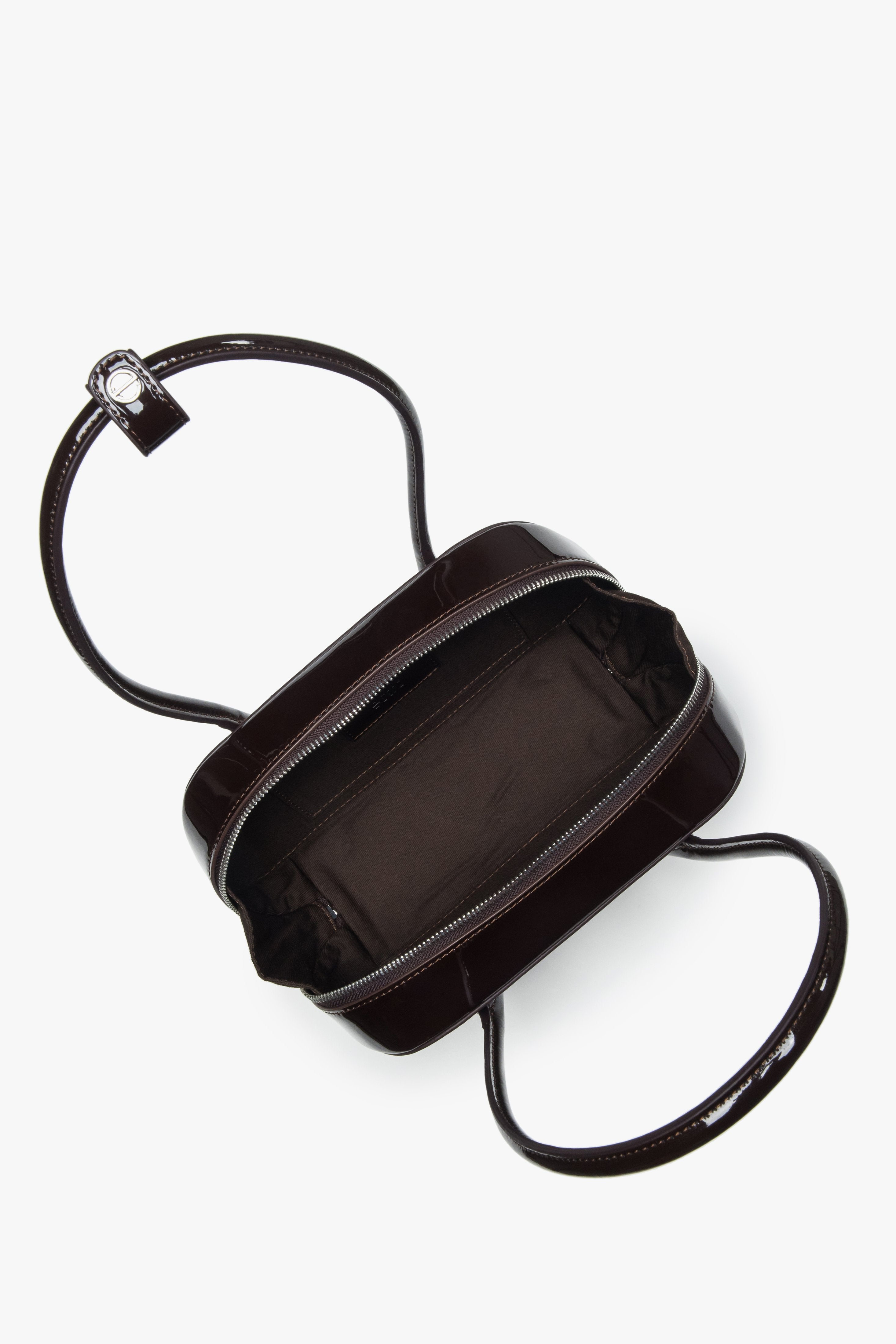 Draufsicht auf die geöffnete Lackledertasche mit Reißverschluss und Logo-Pin am Griff.