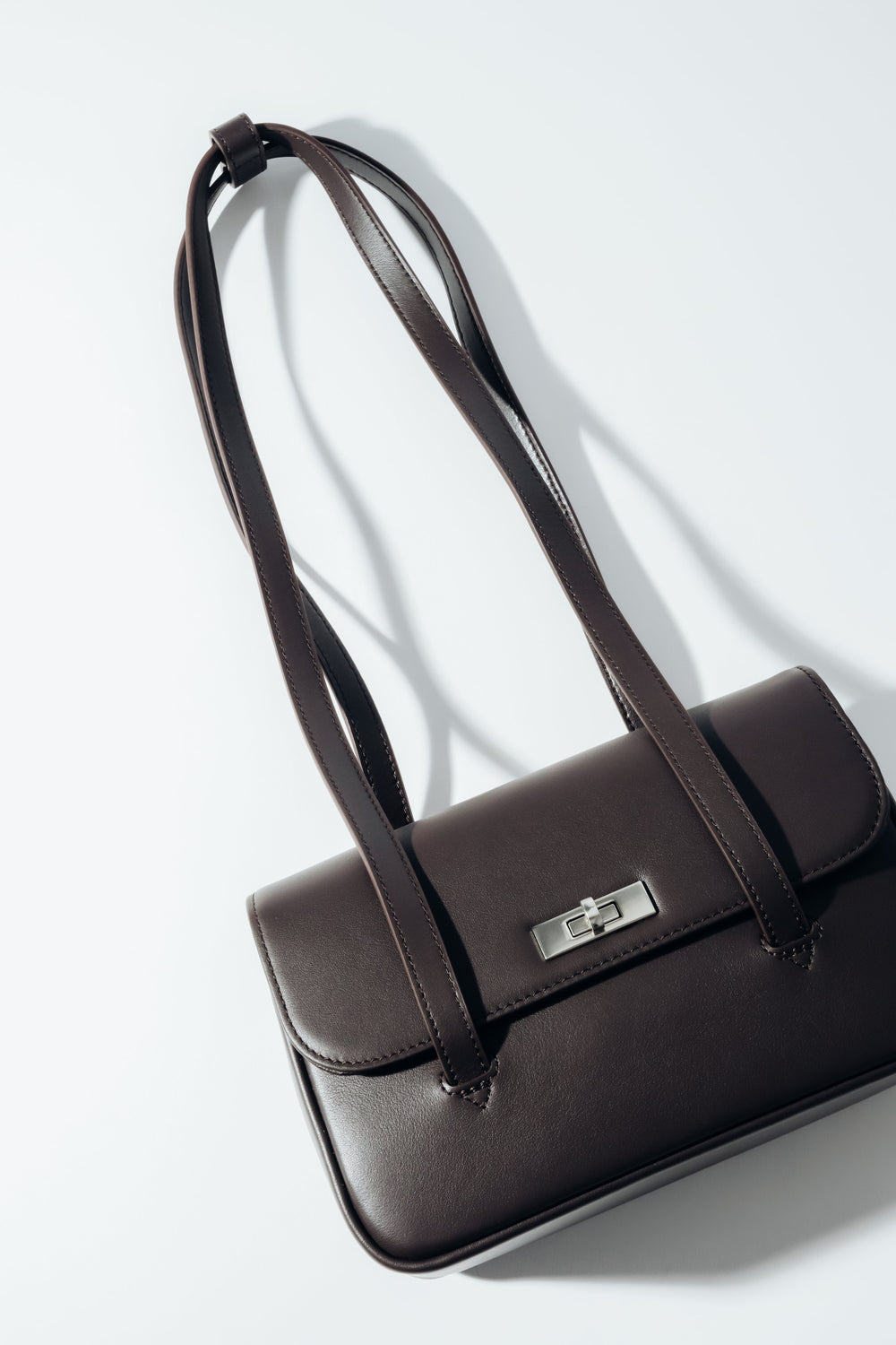 Schräge Aufsicht auf die dunkelbraune Damen-Schultertasche aus Glattleder mit silbernem Drehverschluss