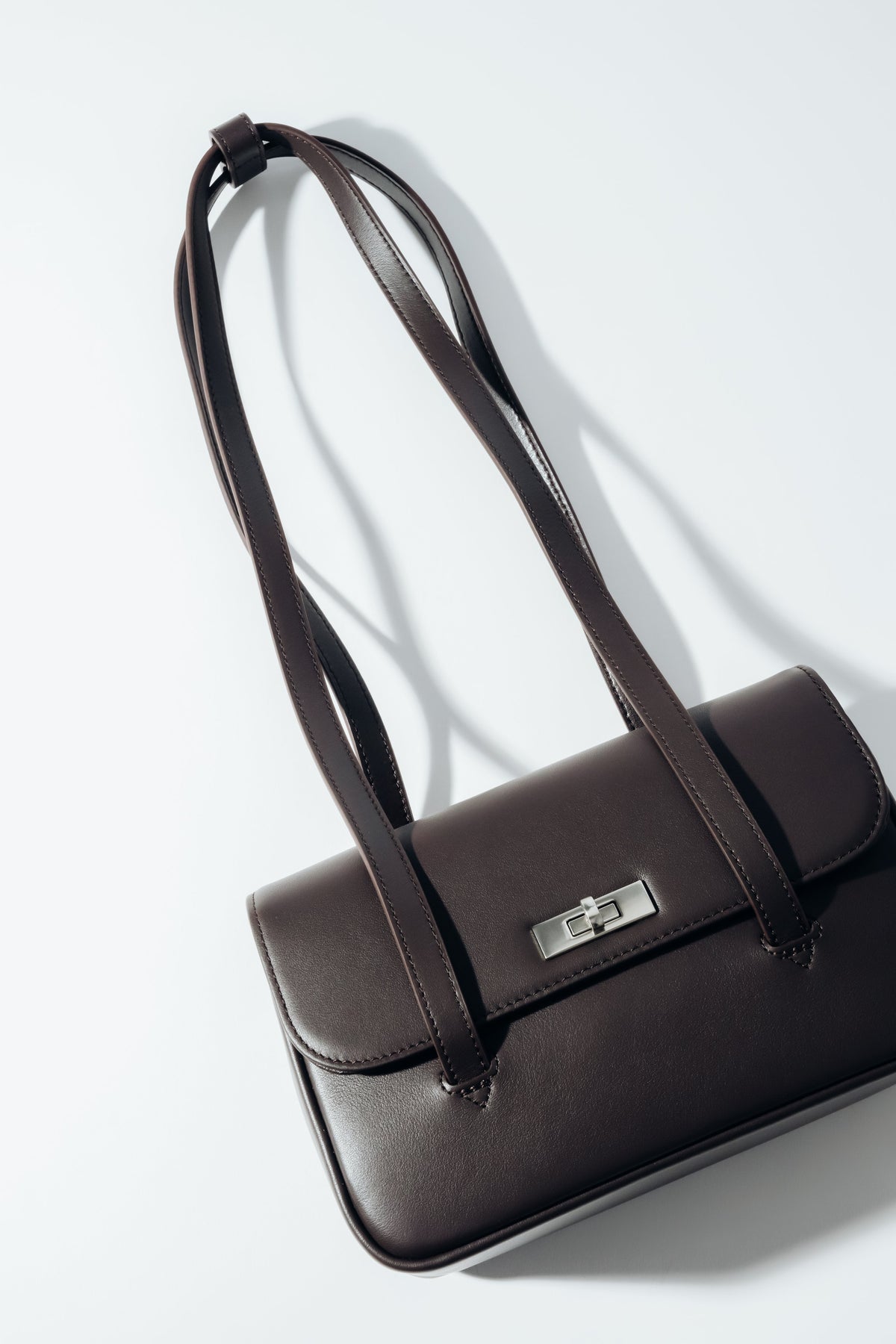 Schräge Aufsicht auf die dunkelbraune Damen-Schultertasche aus Glattleder mit silbernem Drehverschluss