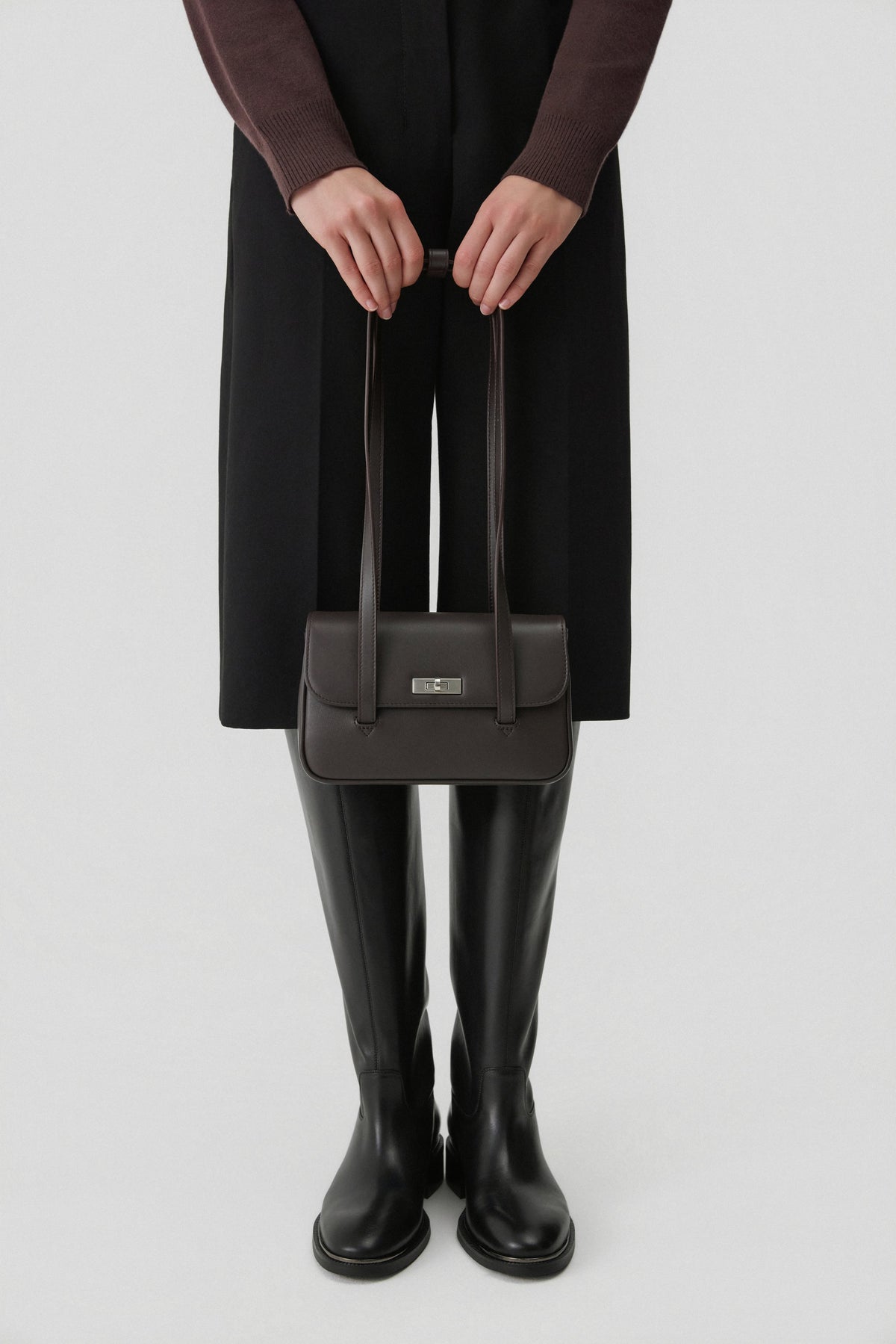 Model in dunklem Outfit hält die formstabile Ledertasche lässig in der Hand