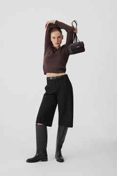 Model steht und trägt die dunkelbraune Ledertasche elegant über der Schulter