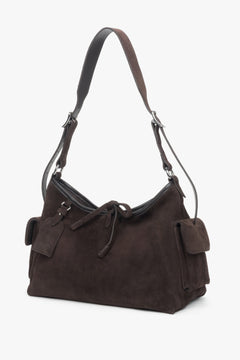 Schräge Ansicht der kompakten Veloursledertasche, die den praktischen Pin an den Henkeln zeigt.
