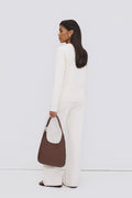 Model in einem weißen Outfit von hinten, trägt die dunkelbraune Echtleder-Shopper-Tasche