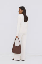 Model in einem weißen Outfit von hinten, trägt die dunkelbraune Echtleder-Shopper-Tasche