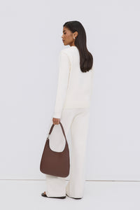 Model in einem weißen Outfit von hinten, trägt die dunkelbraune Echtleder-Shopper-Tasche