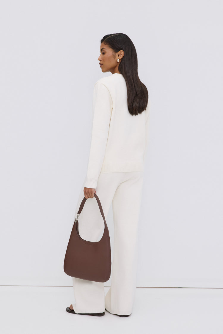 Model in einem weißen Outfit von hinten, trägt die dunkelbraune Echtleder-Shopper-Tasche