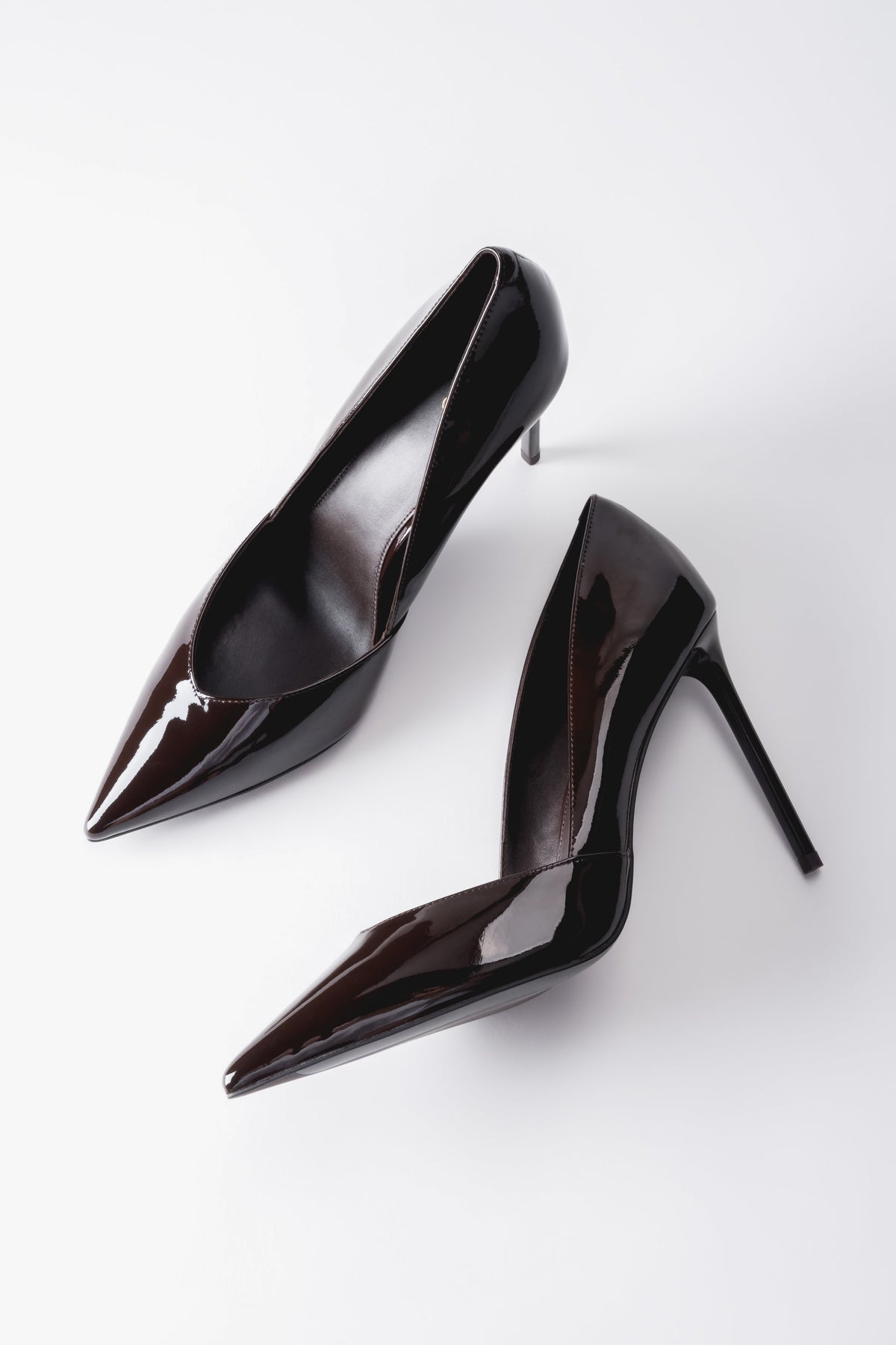 Künstlerische, diagonale Draufsicht auf das Paar dunkelbrauner Damen-Stilettos aus Lackleder