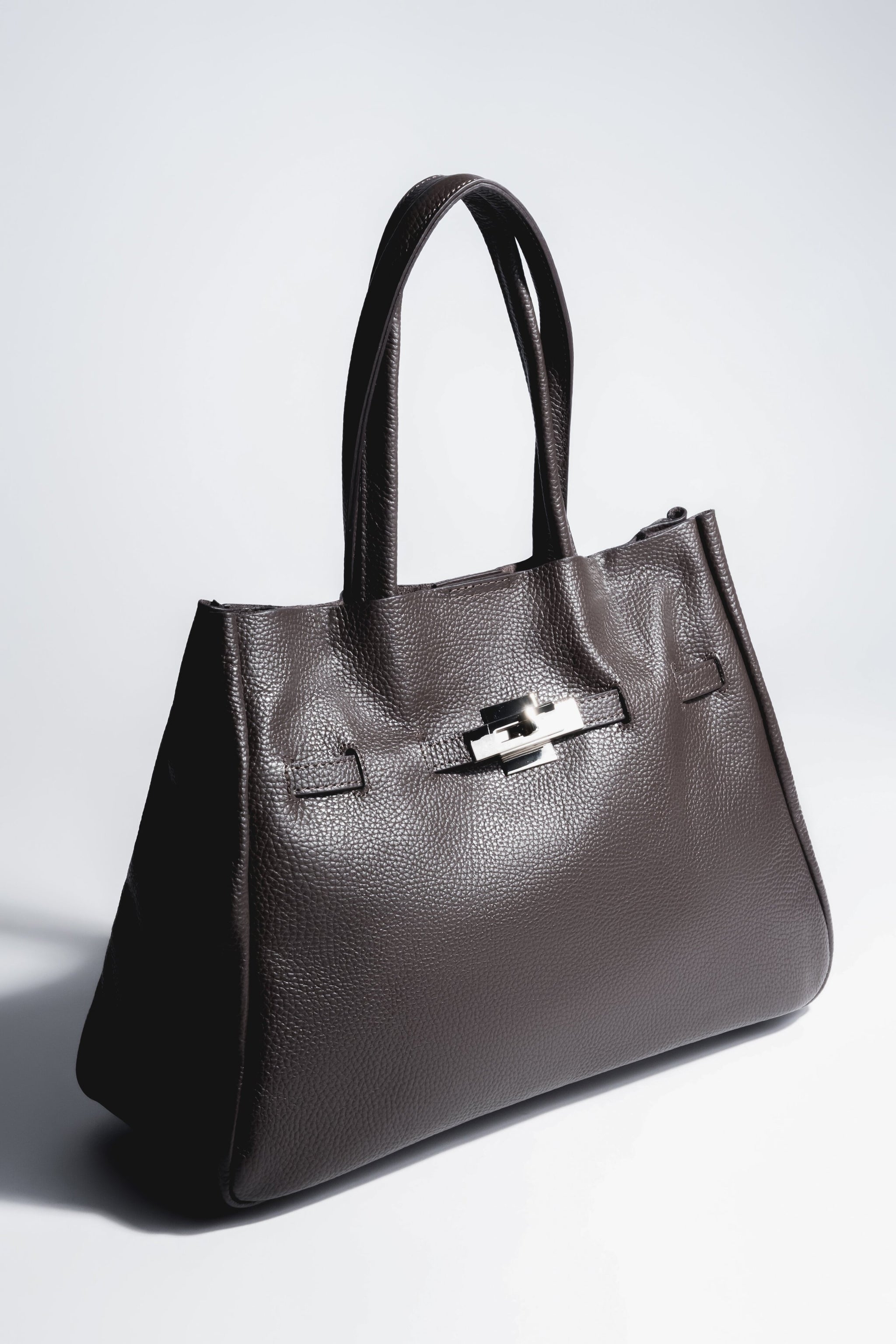 Schrägansicht der dunkelbraunen Damen Tote-Bag aus genarbtem italienischem Echtleder im A4-Format mit kurzen Tragegriffen und silberfarbenem Verschlussdetail