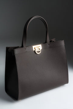 Schräge Frontansicht der dunkelbraunen Damen Tote-Bag aus Naturleder mit goldenem Verschluss.