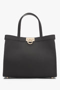 Frontansicht der eleganten Estro Handtasche in Dunkelbraun mit Fokus auf den Logo-Verschluss.