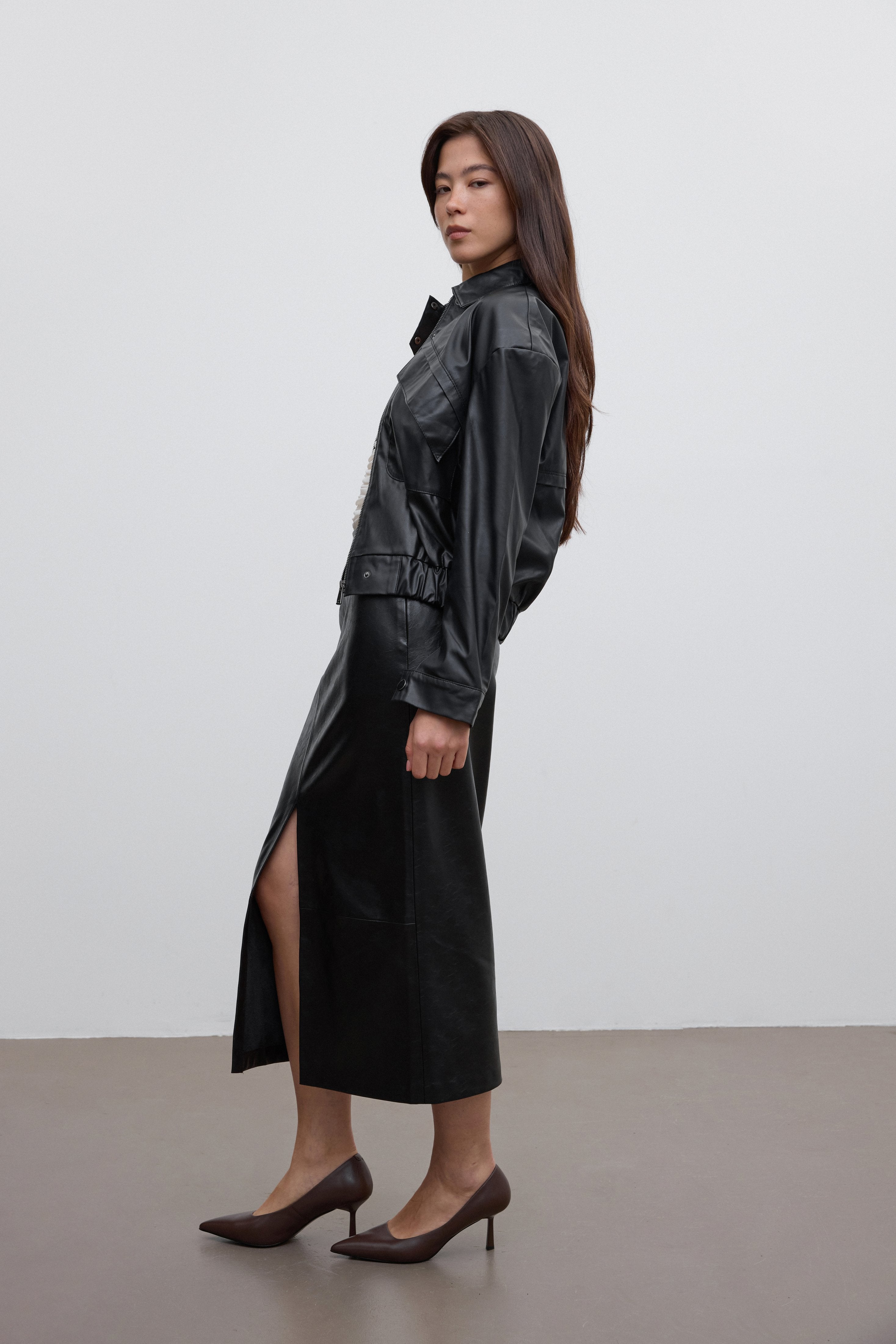 Model trägt die dunkelbraunen Stilettos zu einem eleganten schwarzen Outfit mit Midirock 