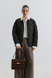 Model mit Steppjacke trägt die dunkelbraune Schultertasche aus italienischem Premium-Velours lässig an der Schulter