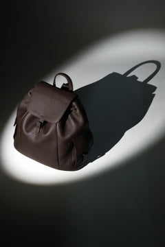 Künstlerische Profilansicht des dunkelbraunen Damen-Beutelrucksacks aus genarbtem Leder im Spotlight