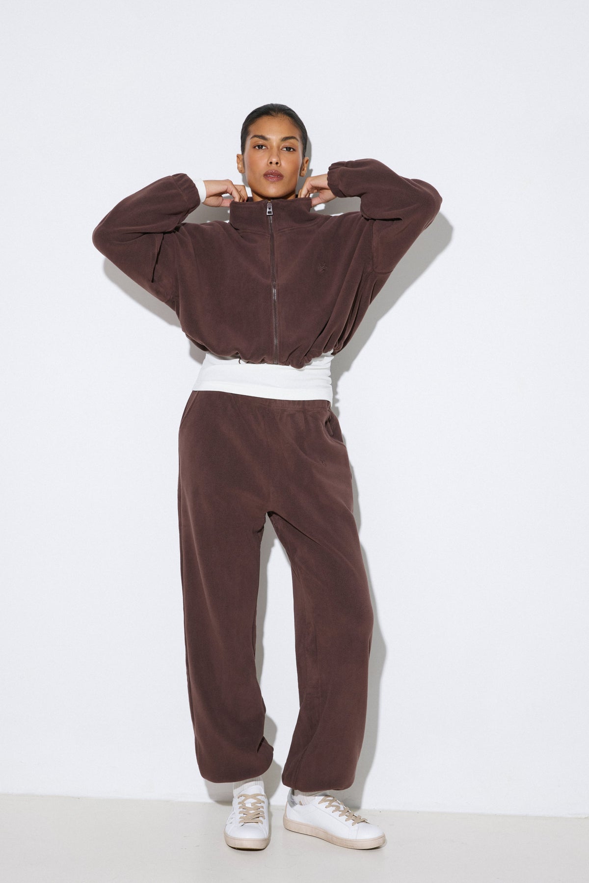 Frontalansicht eines Models im dunkelbraunen Damen-Fleece-Set von Estro, bestehend aus einer Loose-Fit-Jacke und einer lässigen Hose