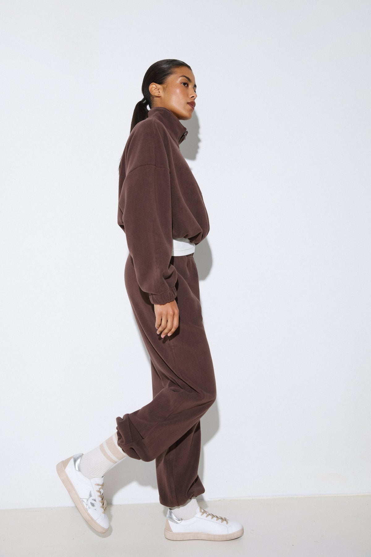 Seitenprofil des dunkelbraunen Damen-Fleece-Sets, das die bequeme Passform und die sportliche Silhouette zeigt