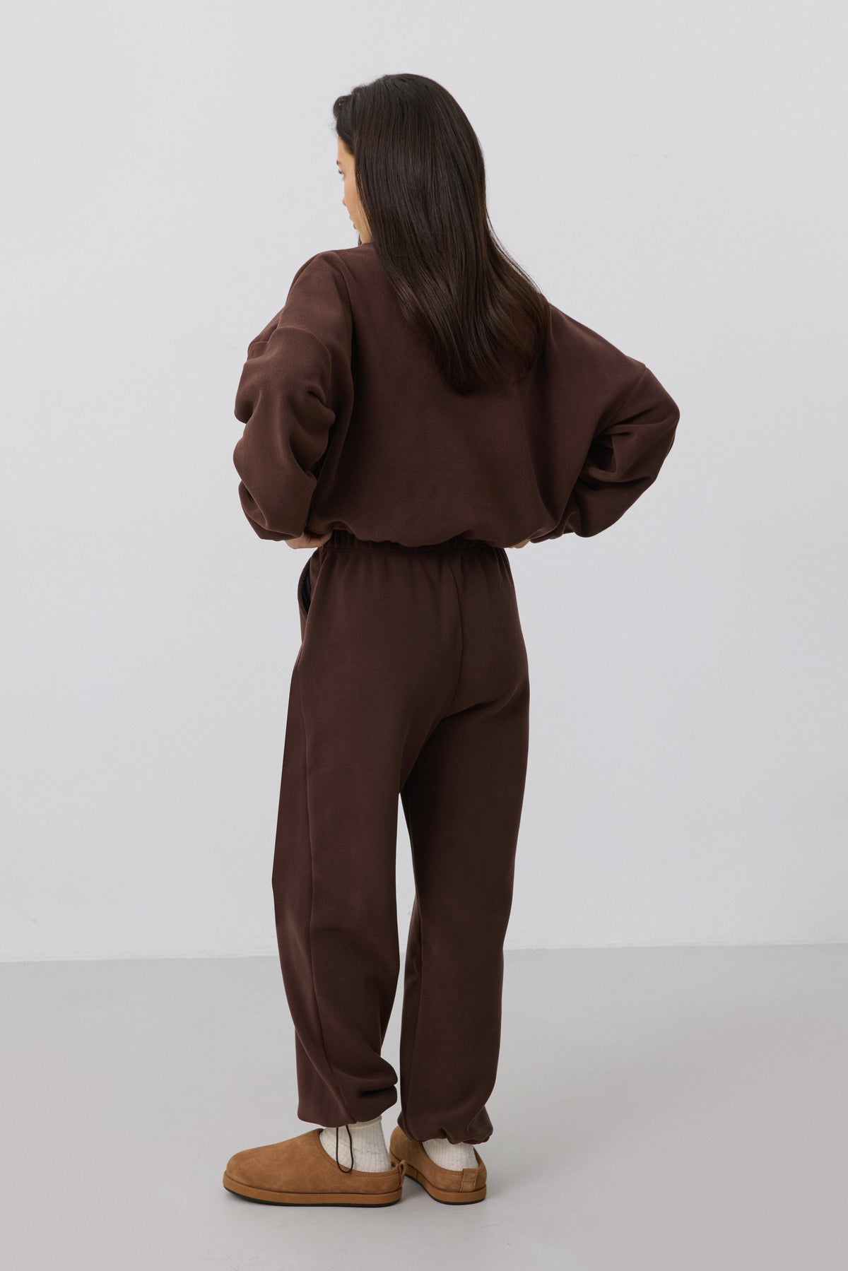 Rückansicht des Models in dem dunkelbraunen Fleece-Set, die den entspannten Loose Fit zeigt